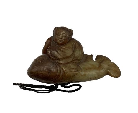 A carved jade figure of a man riding a fish 7cm x 4cm. 