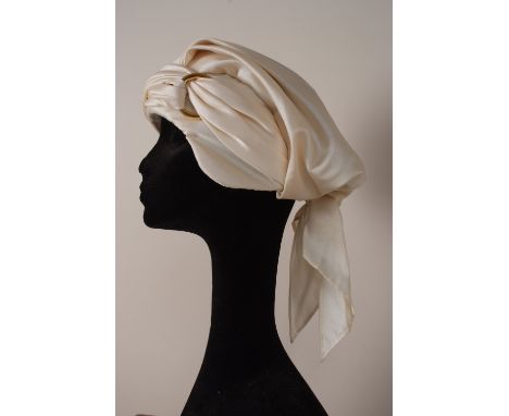 A 1960'S CHRISTIAN DIOR HAT Cream silk turban hat, labelled 'Christian Dior licence chapeaux'.  (1)