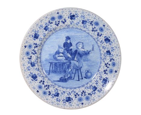 A large Dutch Delft blue and white charger, circa 1900, painted with a Dutch old master tavern scene, within a floral border,