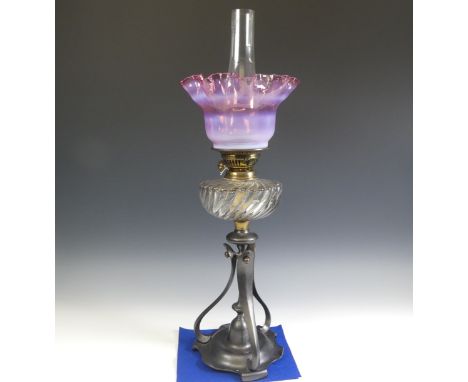 A late 19thC Oil Lamp, with cranberry glass shade, raised on art nouveau style metal base, Rd No. 425960, H 67cm