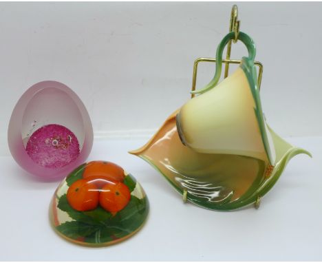 A Franz Porcelain cup and saucer with display stand, a French glass paperweight and one other paperweight 