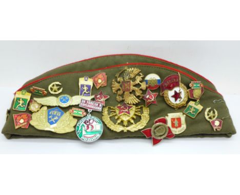 A Russian Army cap with 27 cloth and enamel badges 