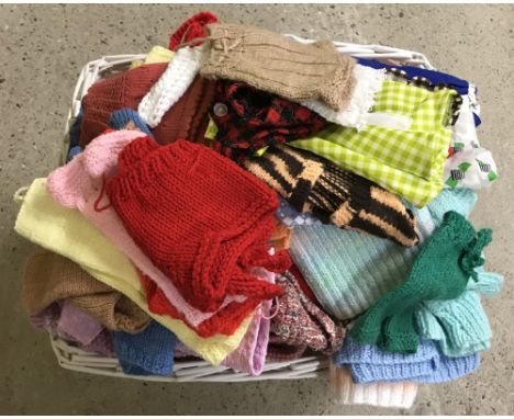 A white wicker basket full of vintage dolls clothes. To include handmade knitted. 