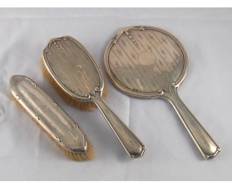 A silver hand mirror, Chester, 1919, a matching hair brush, also a clothes brush with reed and ribbon border by Messrs. Hutto