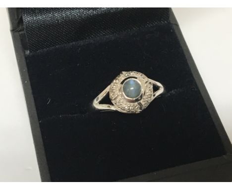 A 9carat white gold ring set with a cabochon flanked by small chip stone diamonds ring size N