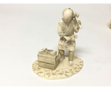 A late 19th century Japanese ivory carving of a craftsman with a chest of tools on a shaped base. Hight 11cm