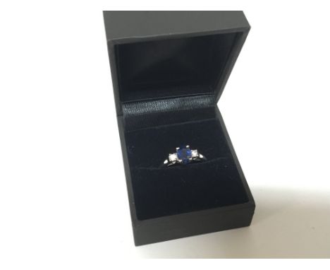 A 9carat white gold ring set with a blue stone possibly a heat treated Sapphire flanked by CZ stones