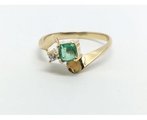 An unmarked gold ring set with a square emerald and a small diamond, approx 1.8g and approx size K.