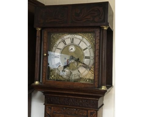 An oak longcase clock with a brass dial and silver chapter ring and carved case the brass dial with date aperture.