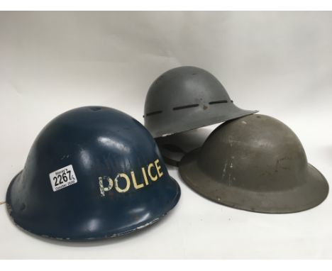 Three tin helmets, including a Police helmet with strap