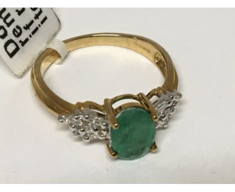 A 9carat gold ring set with an Emerald coloured stone flanked by baguette diamonds. ring size M-N