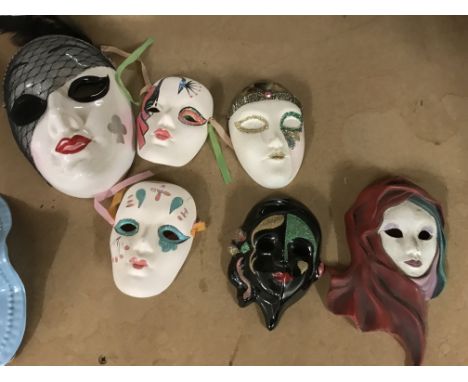 A Art Deco style plaster plaque and a collection of face masks.