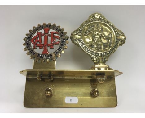 A French badge and St Christopher badge mounted on a brass plate as fitted to a 1904 veteran motor car.