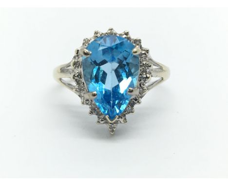 A white gold set with a central topaz surrounded by diamonds, approx 3g and approx size K.