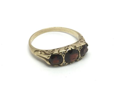 An unmarked gold ring set with three garnets and four small diamonds, approx 2.8g and approx size O.