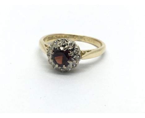 An 18ct gold ring set with a central garnet and surrounded by diamonds, approx 3.3g and approx size K.