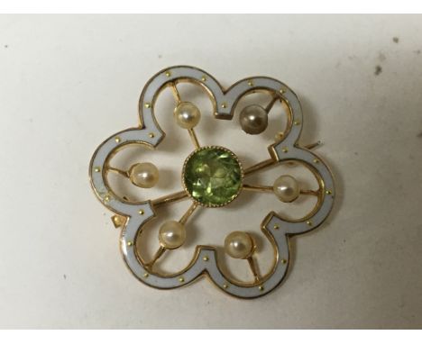 A 15carat gold and white enamel brooch set with pearl and a central green stone possible a green tourmaline. 2.4cm diameter.