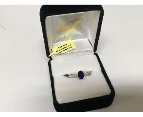 An 18carat white gold ring set with a blue sapphire the shank with small diamonds. Ring size N