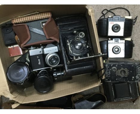 A box of cameras and photographic accessories including a Zenit B SLR, three folding cameras and three Kodak brownies