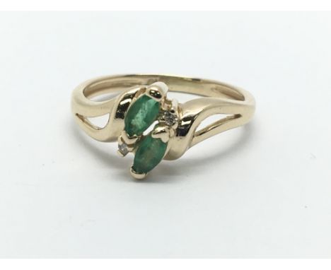 A gold ring set with two emeralds and two small diamonds, approx 2.2g and approx size J-K.