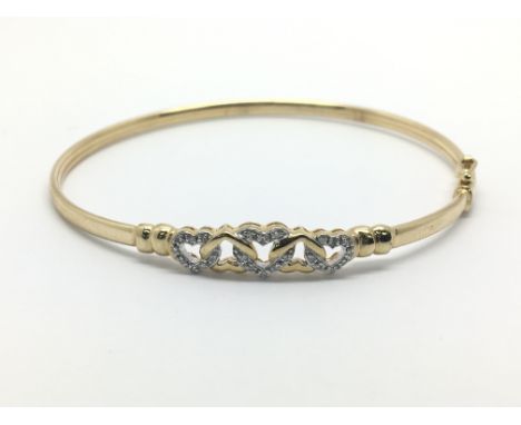 A gold bangle with heart shaped decoration with small diamonds, approx 4.6g.