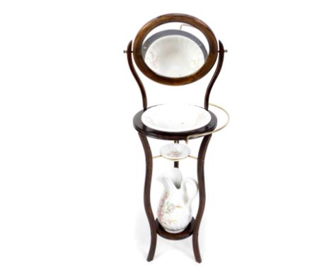 A reproduction stained beech wood three tier wash stand, on slender moulded scroll supports, with adjustable circular mirror,