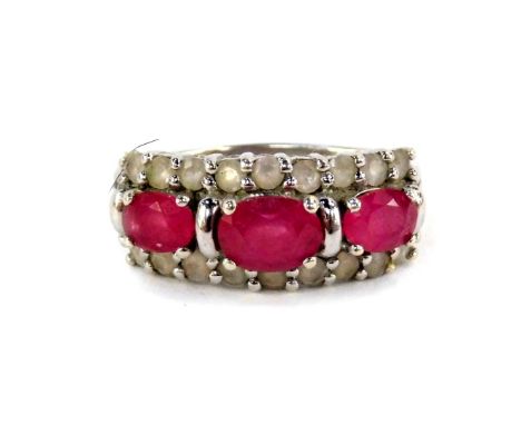 A 9ct white gold ruby and white sapphire ring, the three oval cut rubies flanked by brilliant cut white sapphires, in a claw 