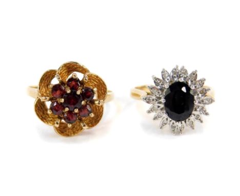 A 9ct gold sapphire and diamond flower head ring, together with a 9ct gold and garnet flower head ring in a textured repeatin