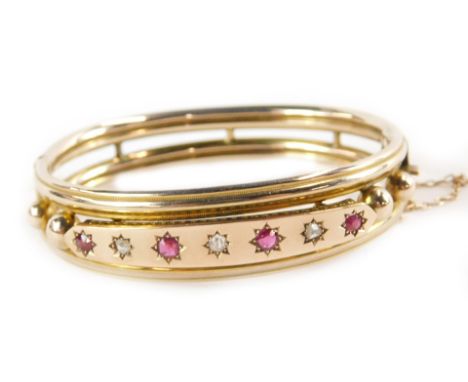 A Victorian diamond and ruby set bangle, in hollow yellow metal, on a snap clasp with safety chain as fitted, cased for J Mor