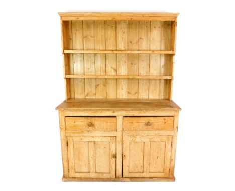 A Victorian pine dresser, the outswept pediment over a waterfall two shelf plate rack, over two drawers above cupboards, rais