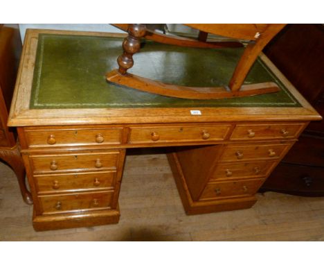 An early 20th Century light oak flat topped kneehole desk, with green leather inset top.