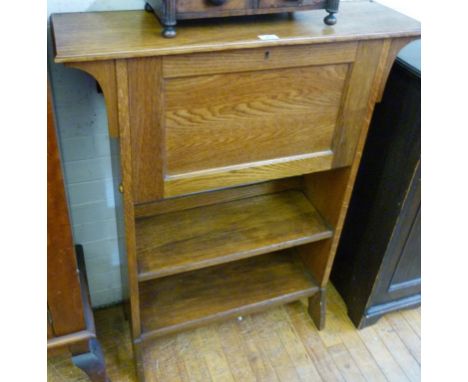 An early 20th Century light oak students bureau having panelled door above single fixed shelf.