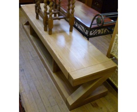 A contemporary solid light oak coffee table of rectangular form, with under tier magazine storage compartments, raised on Z s