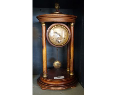 An early 20th Century French Regency style mantel clock, the circular face raised beside four corns.