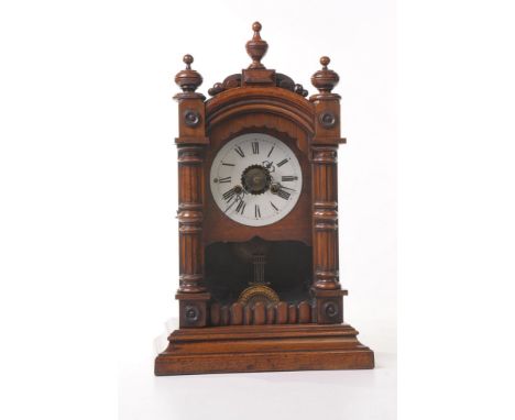 A late 19th Century walnut alarm mantle clock
The Gothic architectural casing with three campana urn finials, the hinged and 