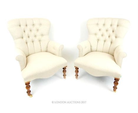 A pair of contemporary Victorian style armchairs, upholstered in light grey button back fabric, raised on turned supports ter
