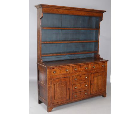 A late George III provincial oak dresser, the shelf back with blue painted backboards, the base with applied brass handles, h