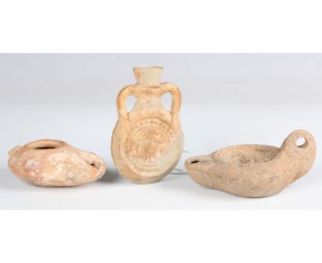 A Roman terracotta twin-handled flask, 4th century AD, height 10cm, together with two Roman pottery oil lamps, one moulded wi