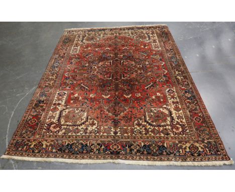 A Heriz carpet, North-west Persia, mid-20th century, the faded red field with a bold medallion, within a turtle palmette and 