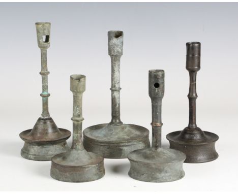 A group of five 16th century patinated metal socket candlestick shafts with later-made wooden bases, height of tallest 19cm (
