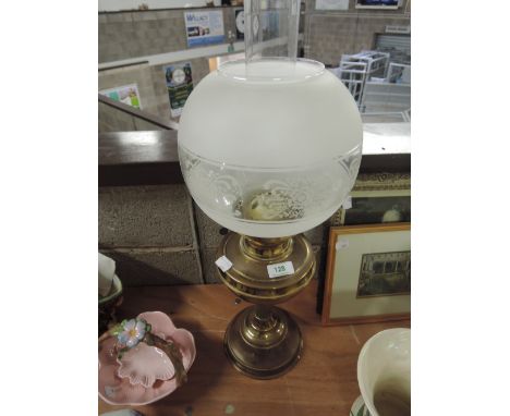 A vintage brass oil lamp with glass shade and chimney