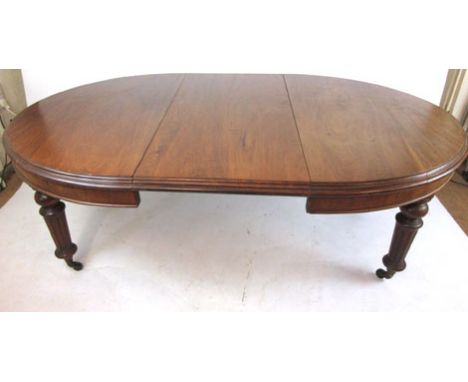 A late 19th century mahogany extendable dining table with a wind out mechanism and two leaf's on turned and fluted legs with 