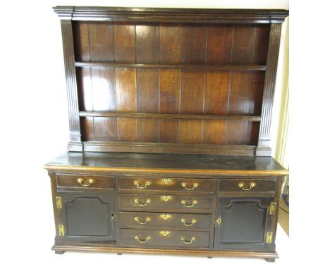 An 18th century and later oak dresser, the plate rack with fluted architectural sides over the base with a row of three drawe