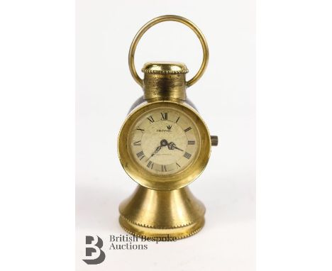 A miniature mechanical desk clock in the shape of a veteran car oil side lamp, approx. 9cms tall. Black and brass finish with