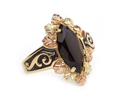 GEM SET DRESS RING, the marquise shaped bezel set with a central black gem within a bi colour foliate motif border, on black 