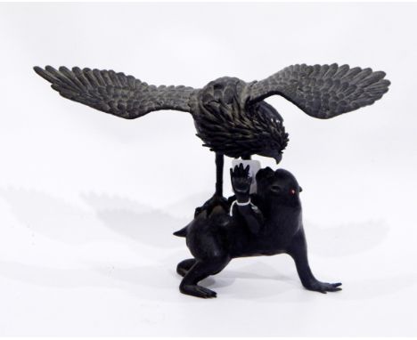 Japanese bronze model of an eagle preying on a monkey, 23cm high on an associated wooden stand 