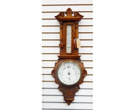 Aneroid barometer and thermometer in carved oak case with floral decoration columns and swan neck pediment 