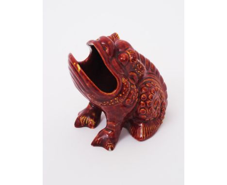 A Burmantoft's Faience grotesque Bull Frog vase, covered in a red glaze over yellow impressed mark, repaired leg and chips, 1
