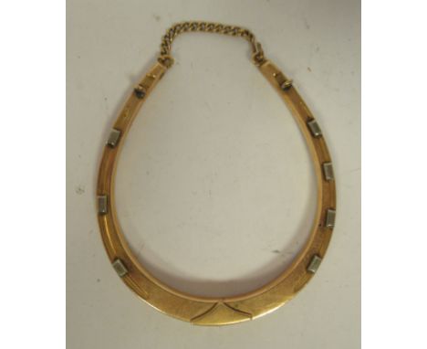 A 10ct bi-coloured gold, sprung bangle in the form of a horseshoe, incorporating a safety chain 