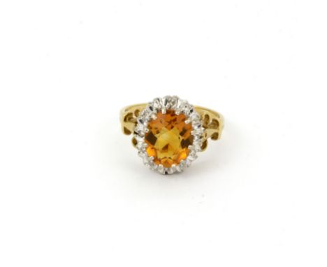 A hallmarked 18ct yellow gold cluster ring set with an oval cut citrine surrounded by diamonds, (Q.5).